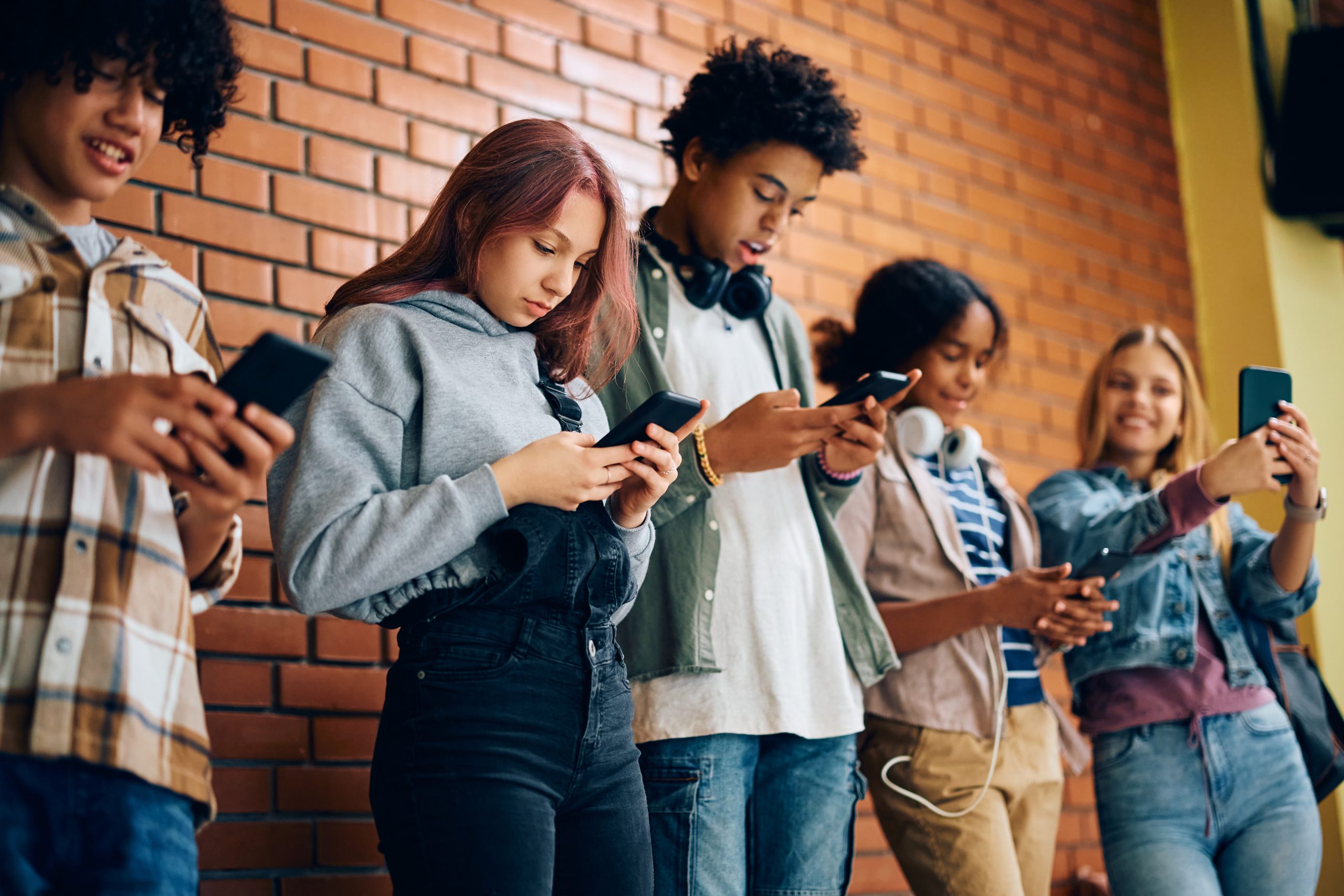 Group of teenagers using their cell phones at high school